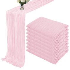 a stack of pink cloths next to a vase with flowers