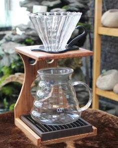 a glass coffee pot sitting on top of a wooden stand