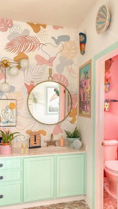 a bathroom decorated in pastel colors with pink, green and gold accents on the walls