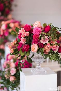 a vase filled with lots of pink and red flowers on top of a white table