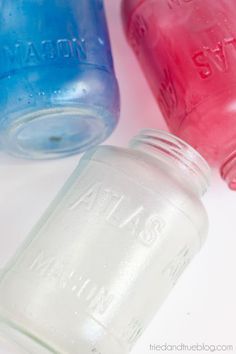 two mason jars sitting next to each other on a white surface with red and blue lids