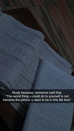 an open book sitting on top of a wooden table next to a pen and paper