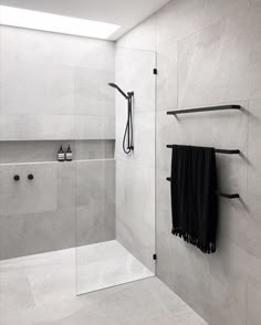 a bathroom with a shower, toilet and black towel hanging on the wall next to it