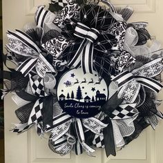 a black and white christmas wreath hanging on a door