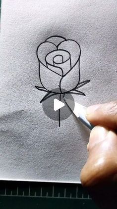 someone is drawing a rose on paper with a marker