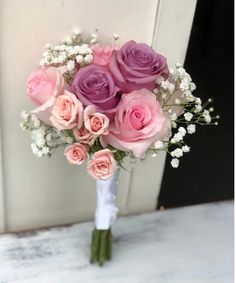 a bouquet of pink roses and baby's breath is sitting on a white table