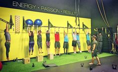 a group of people standing in front of a wall with exercise balls and gym equipment