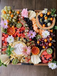 a tray filled with fruit and flowers on top of a wooden table