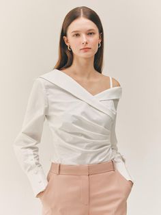 This product is a Miriam one-shoulder shirt blouse that offers a modern twist on classic shirting. The design features an asymmetric neckline that reveals one shoulder, adding an element of allure. The blouse's tailored fit and structured cuffs provide a contrast to the fluidity of the one-shoulder drape, creating a garment that is both unique and sophisticated. - The one-shoulder design presents an elegant take on contemporary shirting.- Tailored to fit, the blouse maintains a professional Elegant White Blouse With Asymmetrical Neckline, Feminine Evening Tops With Asymmetrical Neckline, Feminine Asymmetrical Neckline Top For Evening, Elegant Tops With Asymmetrical Neckline For Work, Chic White Blouse With Asymmetrical Neckline, Spring Formal Blouse With Asymmetrical Neckline, Modern One-shoulder Top For Workwear, Modern One-shoulder Top For Work, Elegant Asymmetrical Off-shoulder Top For Summer