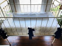 a baby crib with white sheets and black bows on the bottom, in front of a window