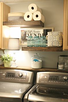 a washer and dryer sitting in a room next to each other with toilet paper on the shelves above them