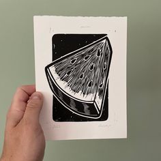 a hand holding up a piece of paper with an image of a slice of watermelon on it