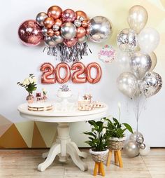 a white table topped with lots of balloons and confetti on top of it