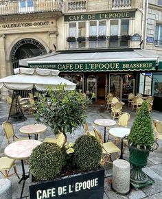 an outdoor cafe with tables, chairs and umbrellas