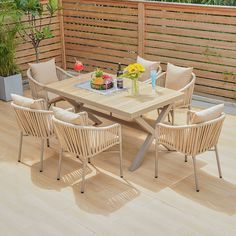 an outdoor table and chairs on a deck with flowers in vases next to it