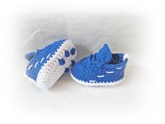 two crocheted blue and white baby shoes sitting next to each other on a white surface