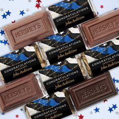 four chocolate bars with congratulations written on them in front of stars and confetti