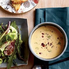 a bowl of soup next to a plate of salad