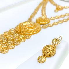 The Layered Dangling Flower 5-Piece Necklace Set, crafted from 21k yellow gold and weighing 83.5 grams, is a masterpiece of jewelry design. This luxurious ensemble features a 26-inch necklace with a dramatic 4.5-inch drop and 4-inch adjustable links, secured by a hook lock. Complemented by matching 1.6-inch earrings with hook backs, a 7.5-inch bracelet with 1-inch adjustable links, and a size 9 ring, all with the same captivating flower motif. This comprehensive set is perfect for those who desi Gold Hand Set Long Bridal Necklace, Gold Bridal Necklace Hand Set, Opulent Gold-plated Gold Jewelry, Opulent Gold-plated Jewelry, Gold Long Bridal Necklace Hand Set, Opulent Gold Necklace For Festive Season, Opulent Gold Jewelry For Ceremonial Occasions, Opulent Gold Ceremonial Jewelry, Ceremonial Gold Long Temple Necklace