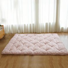 there is a large pink mattress on the floor in front of a window with white curtains