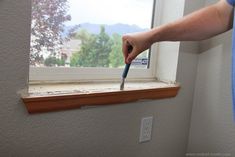 a person holding a paintbrush in front of a window