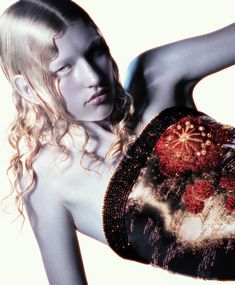 a naked woman holding a purse with flowers on it's side and her arm behind her back