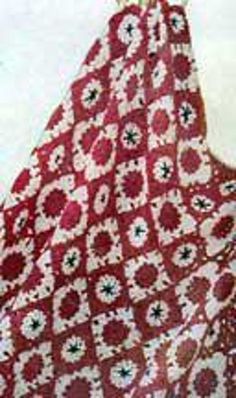 a red and white crocheted blanket with flowers on it