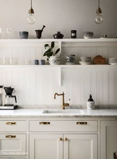 a kitchen with white cabinets and gold pulls on the cupboards is pictured in this image