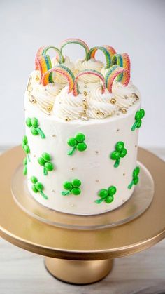 a cake with white frosting and green decorations on a gold plated platter