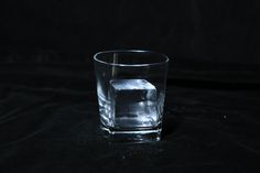 an ice cube in a glass on a black background