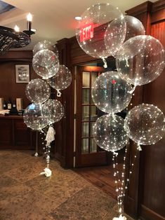 some clear balloons are hanging from the ceiling in front of a bar with lights on it