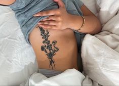 a woman laying in bed with her back turned to the side and flowers on her stomach