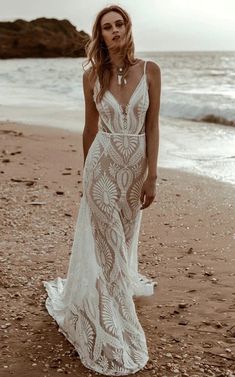 a woman standing on top of a beach next to the ocean wearing a white dress