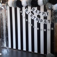 a black and white striped birthday backdrop with pom poms