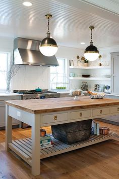 a kitchen with an island in the middle and two pendant lights hanging from the ceiling