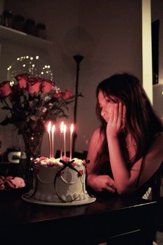 a woman sitting in front of a cake with candles on it