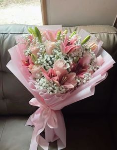 a bouquet of pink and white flowers sitting on a couch next to a glass window