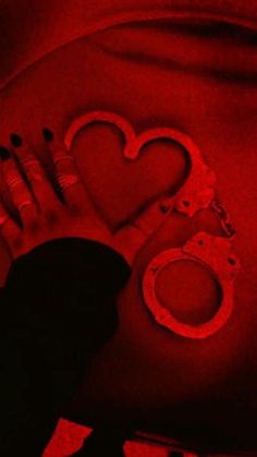 a woman laying on her stomach with handcuffs and heart shaped cutouts in red light