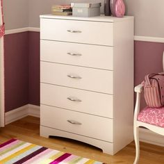 a white chest of drawers sitting next to a pink chair in a room with purple walls