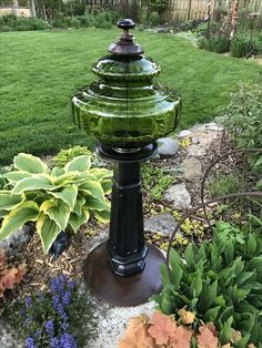 a green glass water fountain sitting in the middle of a garden