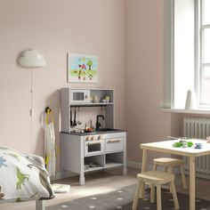 a child's bedroom with pink walls and white furniture, including a small wooden table