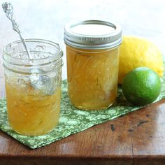 two jars filled with liquid sitting on top of a wooden table next to lemons