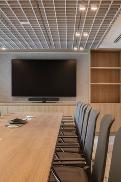 an empty conference room with a flat screen tv on the wall and chairs in front of it