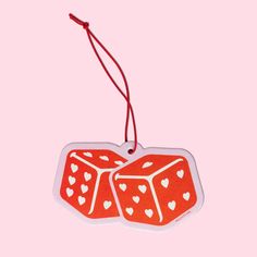 two red dice shaped ornament with hearts on them, hanging from a string