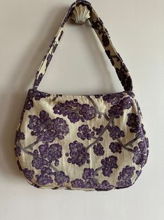 a purse hanging on the wall with purple and white flowers printed on it's side