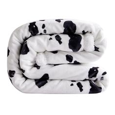 a cow print blanket with black and white spots on the top, folded up in two sections