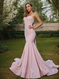 a woman in a pink dress posing for the camera with her hands on her hips