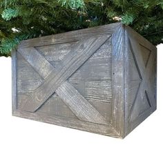 a wooden box sitting on top of a christmas tree with the bottom cut out to look like an x