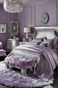 a bedroom decorated in purple and silver with fur rugs on the floor, chandelier