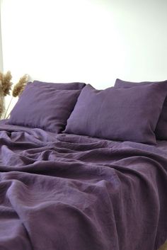 a teddy bear sitting on top of a bed with purple sheets